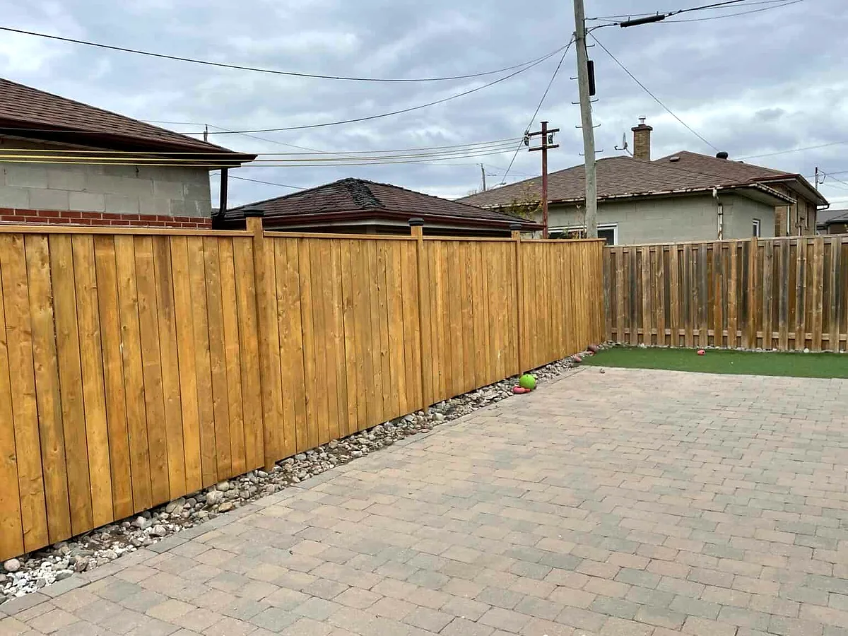 A new cedar privacy fence along a paver patio in a backyard